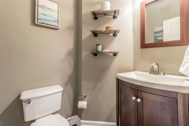 bathroom featuring toilet, vanity, and a textured wall