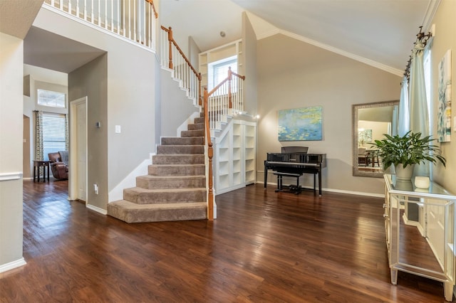 stairway with baseboards, high vaulted ceiling, and wood finished floors