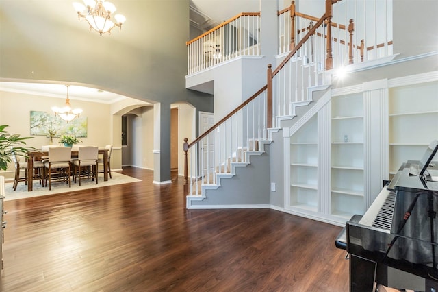 interior space featuring wood finished floors, arched walkways, ornamental molding, stairs, and a chandelier