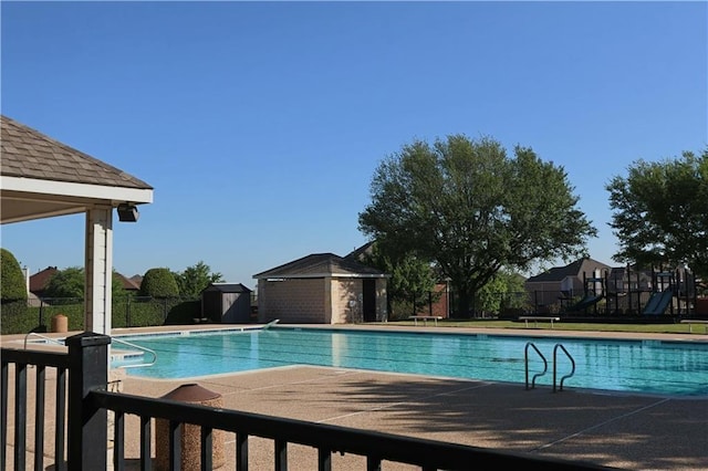 community pool with an outbuilding, a shed, a patio, and fence