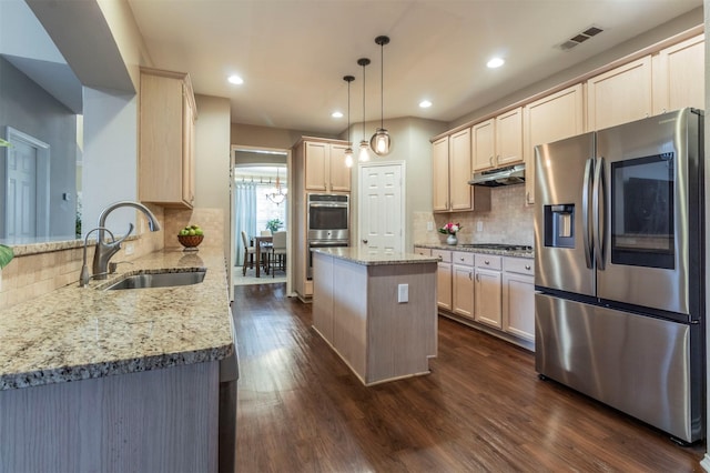 kitchen with light stone countertops, a sink, dark wood-type flooring, under cabinet range hood, and appliances with stainless steel finishes