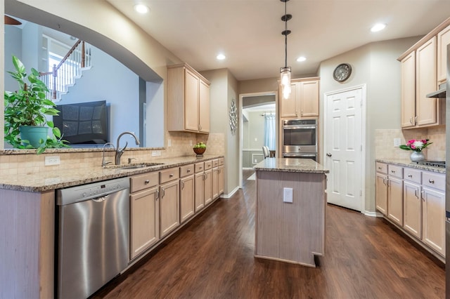 kitchen with light stone counters, a sink, dark wood-type flooring, dishwasher, and a center island