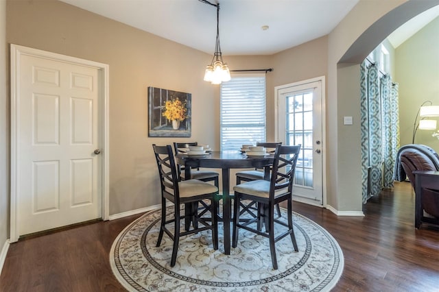 dining space featuring baseboards, arched walkways, and dark wood-style flooring