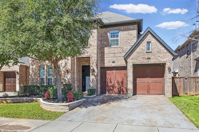 view of front of house with brick siding, decorative driveway, an attached garage, and fence