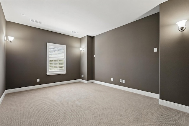 spare room with light carpet, visible vents, and baseboards