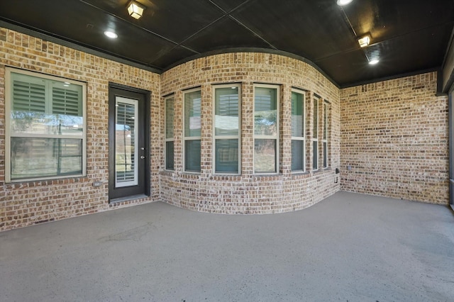 doorway to property featuring a patio area and brick siding