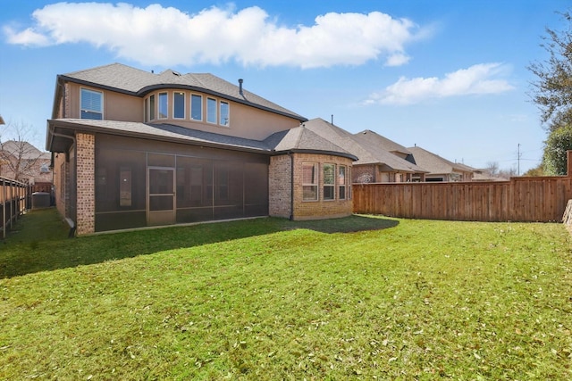 back of property with a lawn, a fenced backyard, a sunroom, and stucco siding