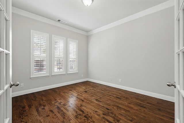 spare room featuring baseboards, visible vents, dark wood finished floors, and crown molding