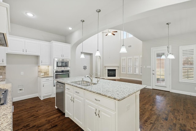 kitchen with a ceiling fan, dark wood-style flooring, a sink, stainless steel appliances, and backsplash