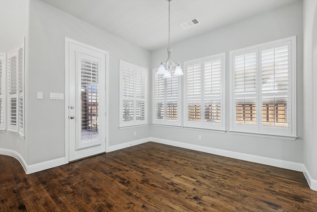 unfurnished dining area featuring baseboards, visible vents, dark wood finished floors, and a chandelier