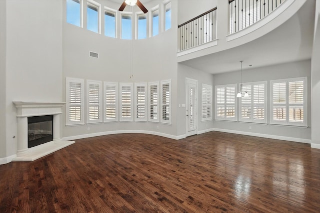 unfurnished living room with visible vents, ceiling fan, baseboards, and wood finished floors