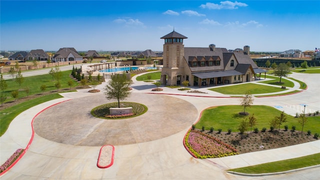 view of property's community with curved driveway and a lawn