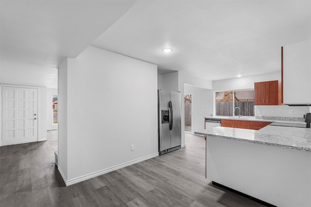 kitchen featuring wood finished floors, baseboards, stainless steel fridge with ice dispenser, range, and brown cabinets