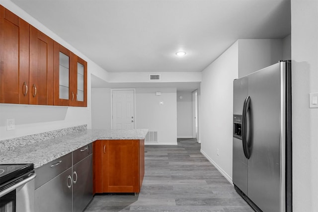 kitchen featuring a peninsula, visible vents, stainless steel appliances, and glass insert cabinets