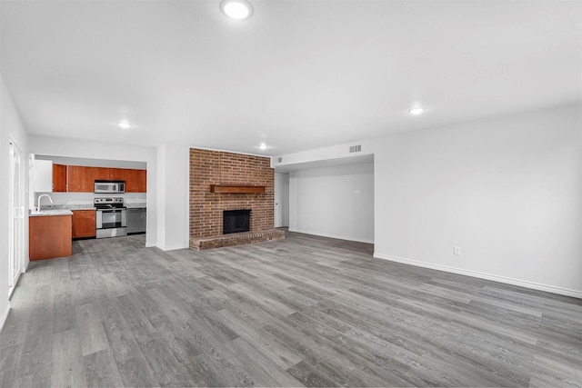 unfurnished living room featuring baseboards, a fireplace, visible vents, and wood finished floors