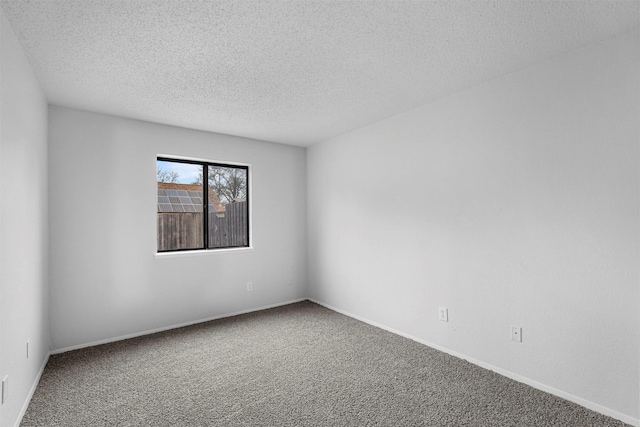 carpeted empty room featuring a textured ceiling and baseboards