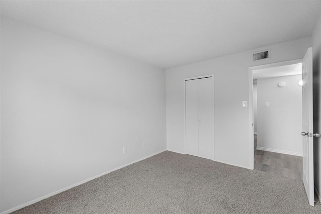 unfurnished bedroom with carpet floors, a closet, visible vents, and baseboards