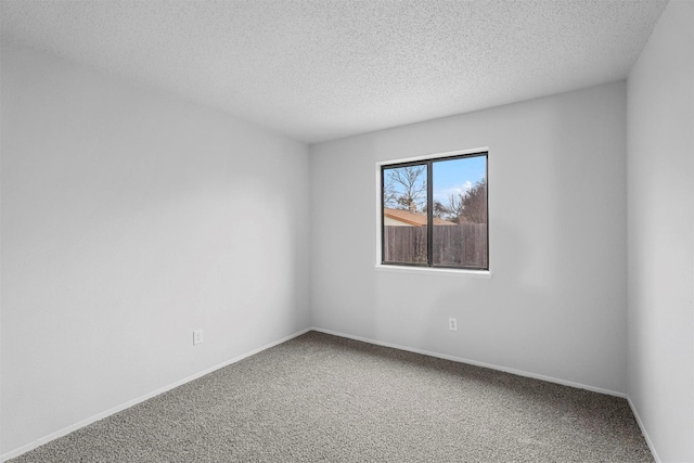 spare room with a textured ceiling, carpet flooring, and baseboards