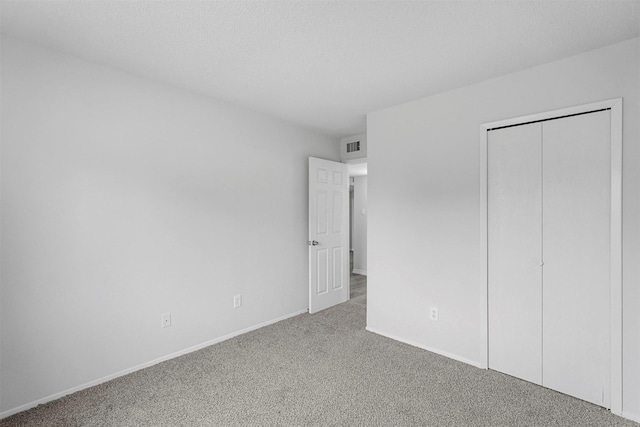 unfurnished bedroom featuring a closet, carpet flooring, a textured ceiling, and baseboards