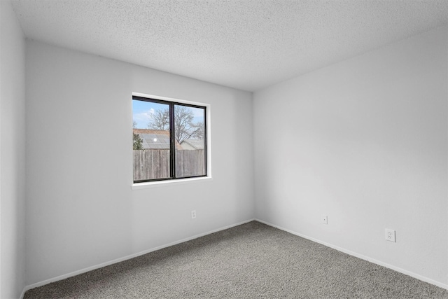 carpeted empty room featuring a textured ceiling and baseboards