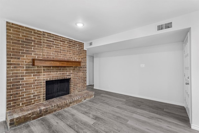 unfurnished living room with baseboards, a fireplace, visible vents, and wood finished floors