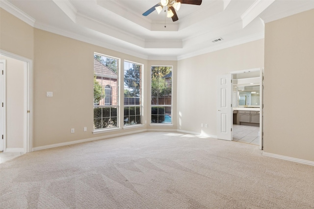 carpeted spare room with baseboards, visible vents, a raised ceiling, ceiling fan, and ornamental molding