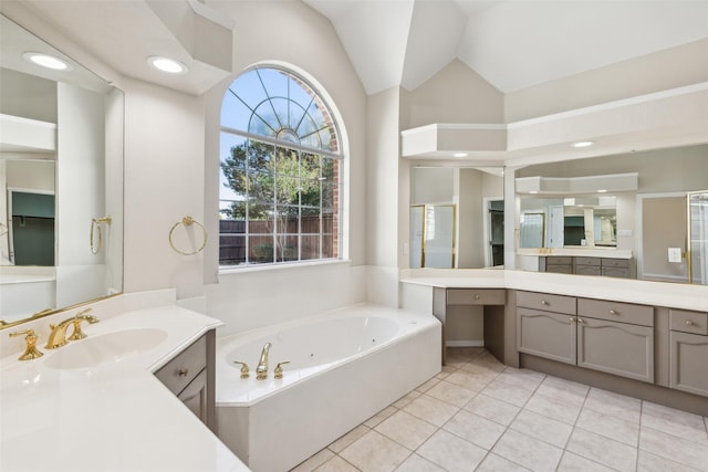 full bath featuring two vanities, a sink, vaulted ceiling, tile patterned floors, and a whirlpool tub