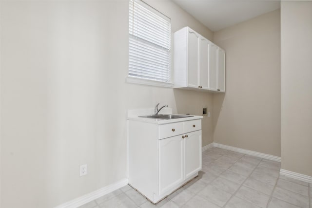 laundry room featuring hookup for a washing machine, cabinet space, baseboards, and a sink