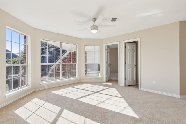 unfurnished room with carpet, visible vents, ceiling fan, and baseboards