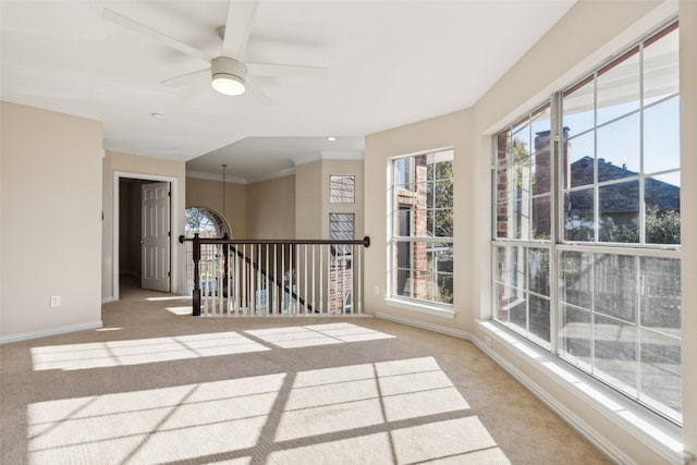 carpeted spare room with ceiling fan, ornamental molding, and baseboards