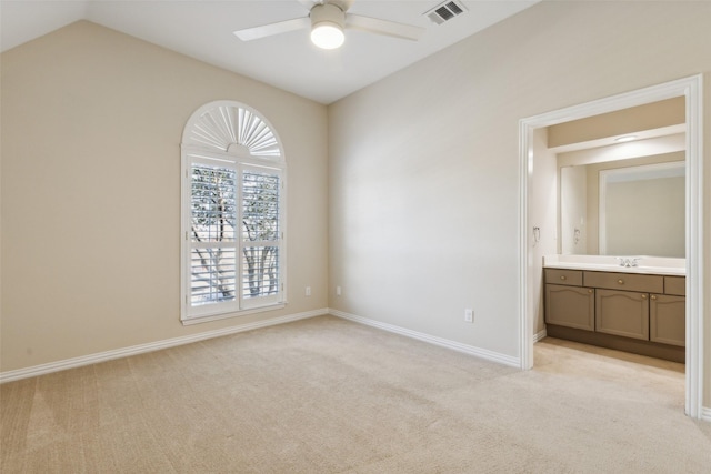 unfurnished bedroom with baseboards, visible vents, light colored carpet, ensuite bath, and vaulted ceiling