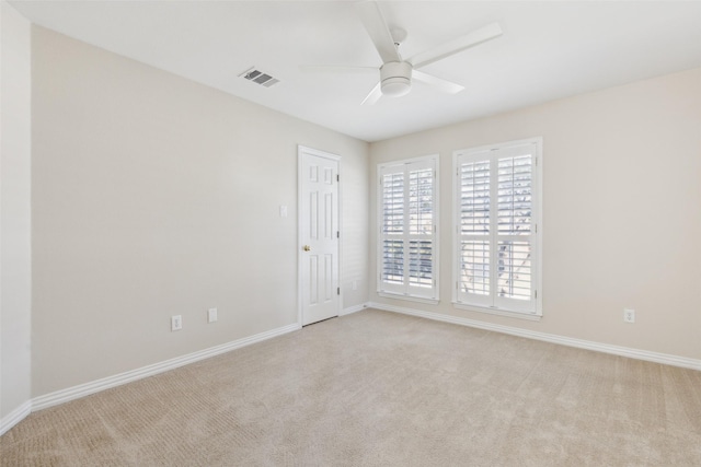 unfurnished room with baseboards, a ceiling fan, visible vents, and light colored carpet