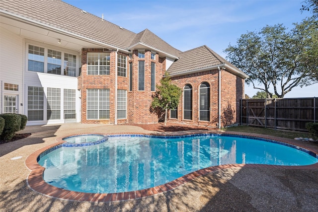 view of pool with a patio, fence, and a pool with connected hot tub