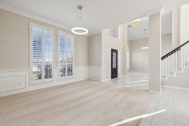 empty room featuring ornamental molding, light colored carpet, a healthy amount of sunlight, and stairway