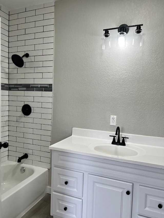 bathroom featuring a textured wall, wood finished floors, bathtub / shower combination, and vanity