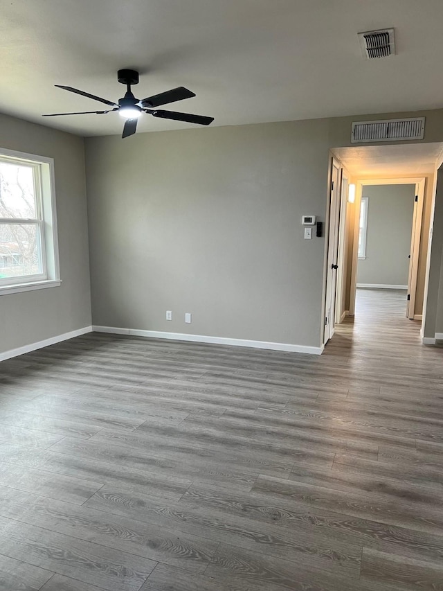 spare room featuring dark wood finished floors, visible vents, and baseboards