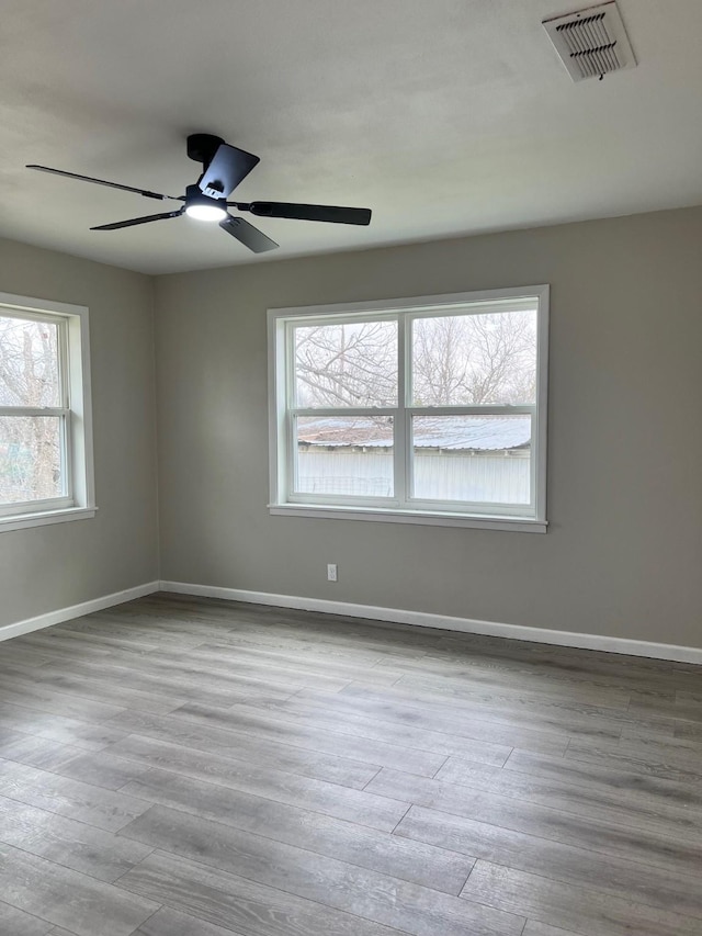 empty room featuring visible vents, ceiling fan, baseboards, and wood finished floors