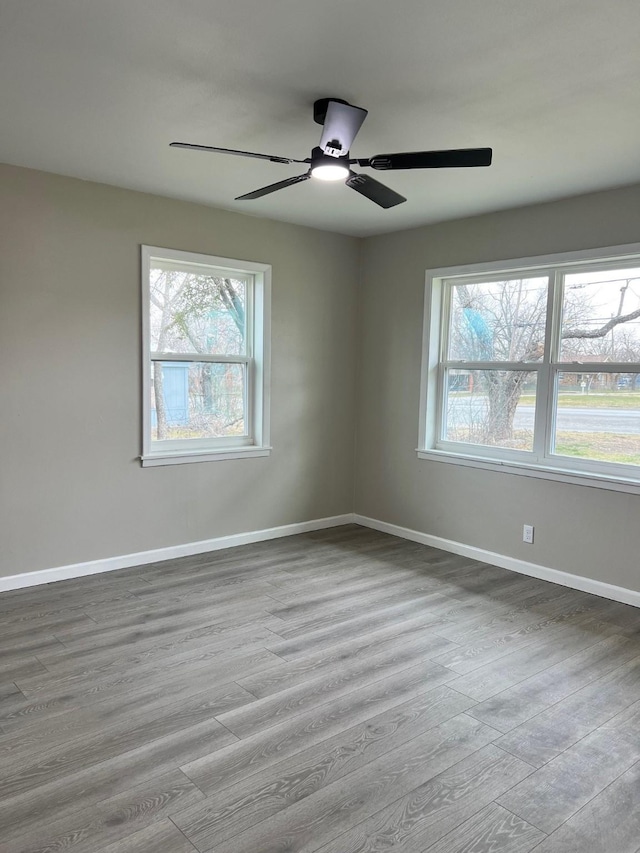 unfurnished room featuring plenty of natural light, wood finished floors, and baseboards