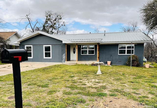 ranch-style home featuring metal roof, brick siding, and a front yard