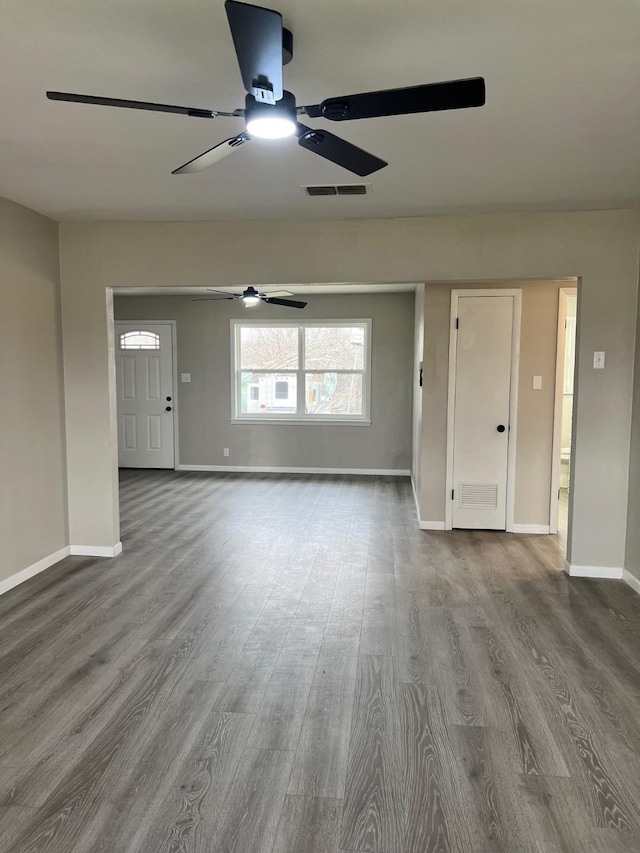 unfurnished living room with wood finished floors, visible vents, and baseboards