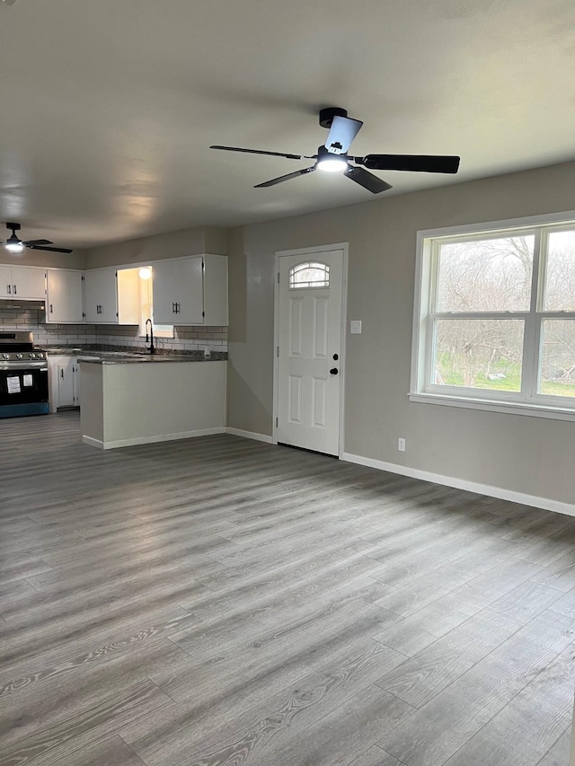 kitchen featuring open floor plan, stainless steel electric range oven, backsplash, and wood finished floors