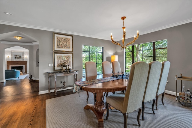 dining room with a chandelier, ornamental molding, a fireplace, and baseboards