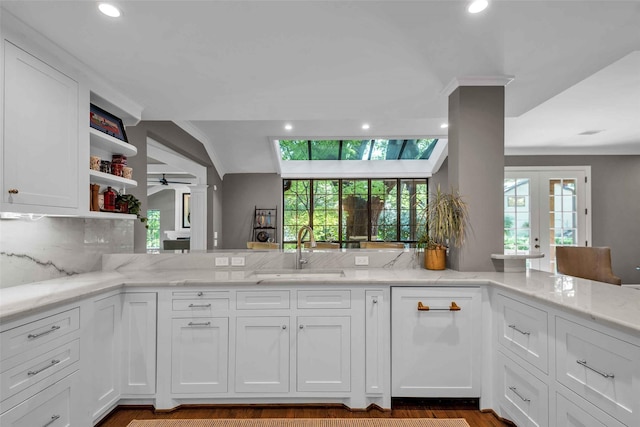 kitchen featuring plenty of natural light, white cabinets, a sink, and light stone countertops