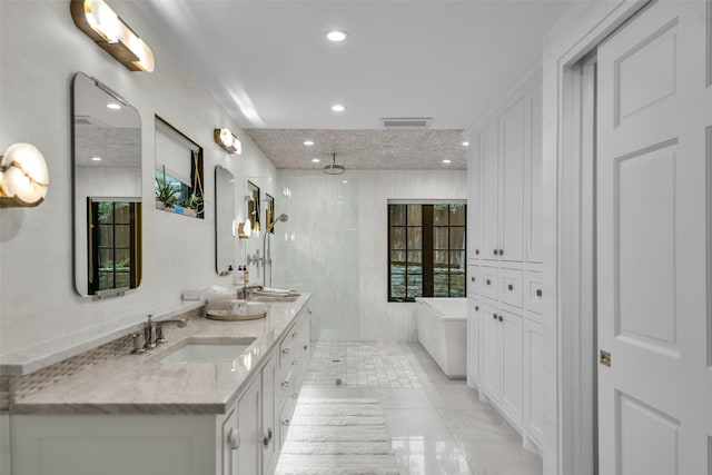 bathroom with double vanity, visible vents, a soaking tub, a tile shower, and a sink