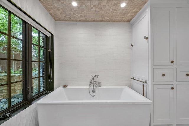 full bathroom featuring recessed lighting, a soaking tub, and tile walls