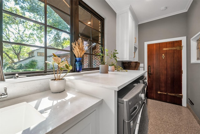 washroom featuring cabinet space, ornamental molding, a sink, and independent washer and dryer