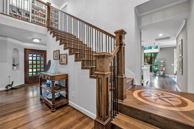 staircase with baseboards, visible vents, wood finished floors, and ornamental molding