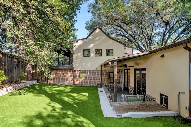 back of house featuring a yard, a fenced backyard, ceiling fan, and stucco siding