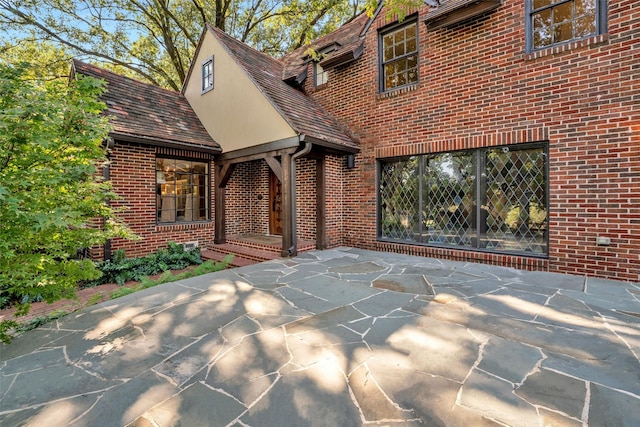 exterior space with a patio area, brick siding, and stucco siding