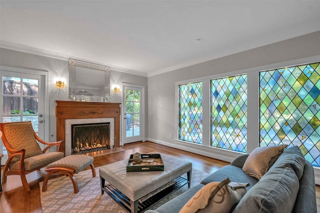 living area with crown molding, baseboards, wood finished floors, and a high end fireplace